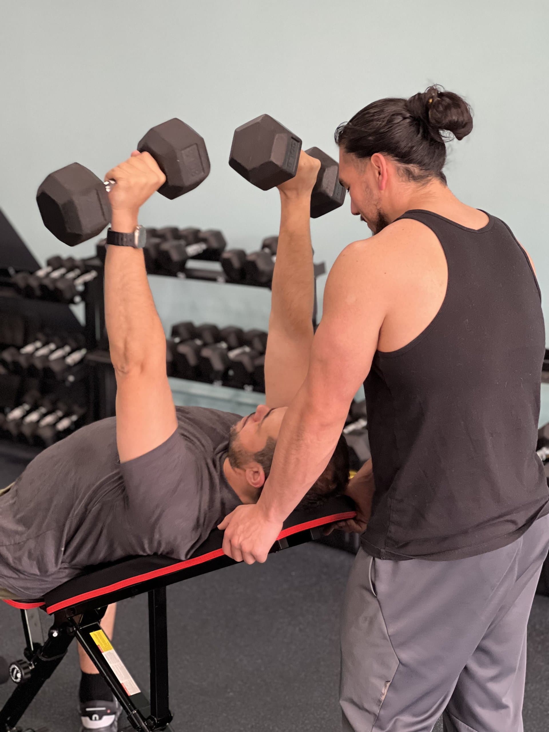 Personal trainer coaching a client through a dumbbell press at Grit Life Fitness in Canton, GA