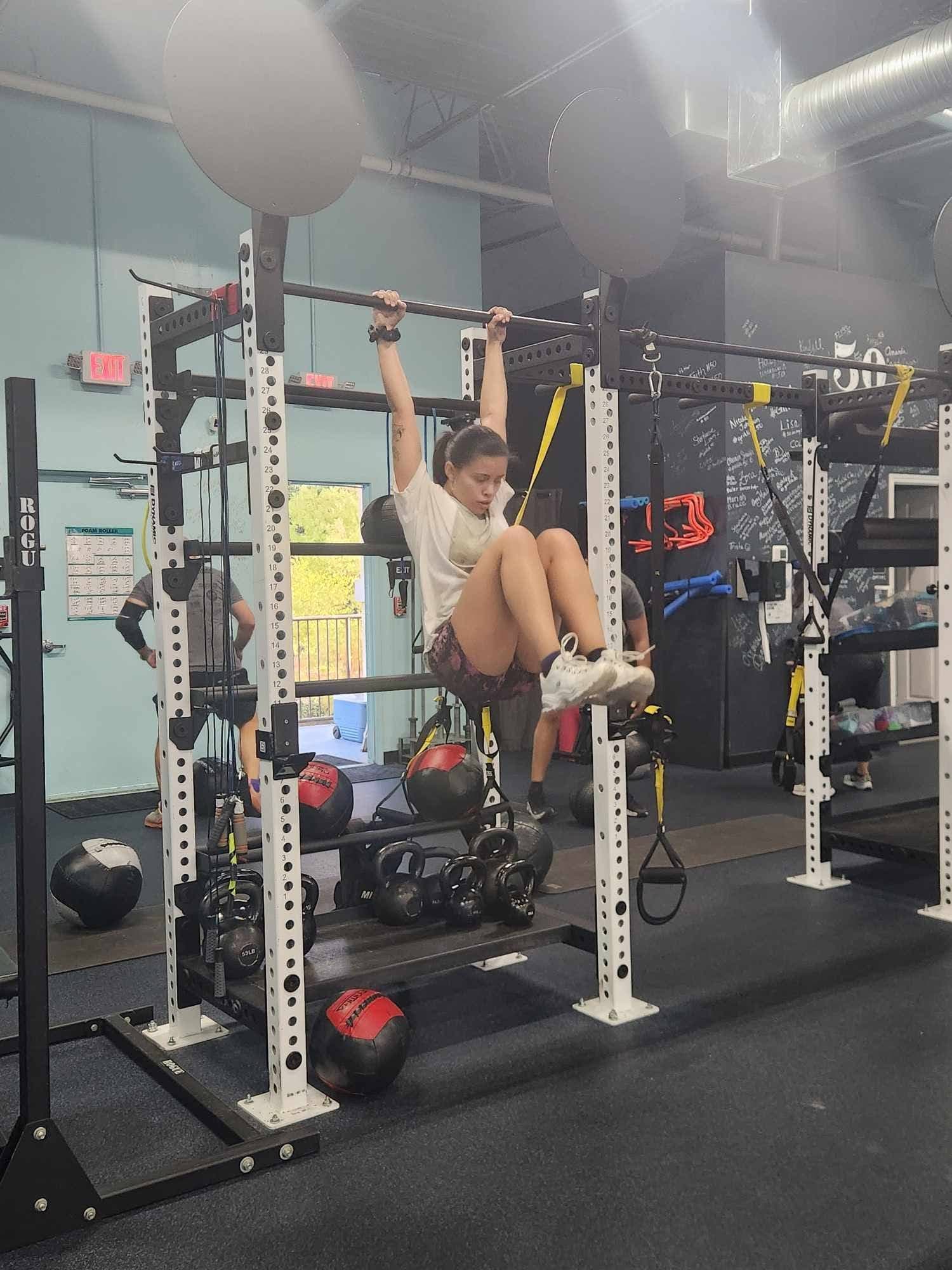 A participant performing hanging knee raises on the rig during the event