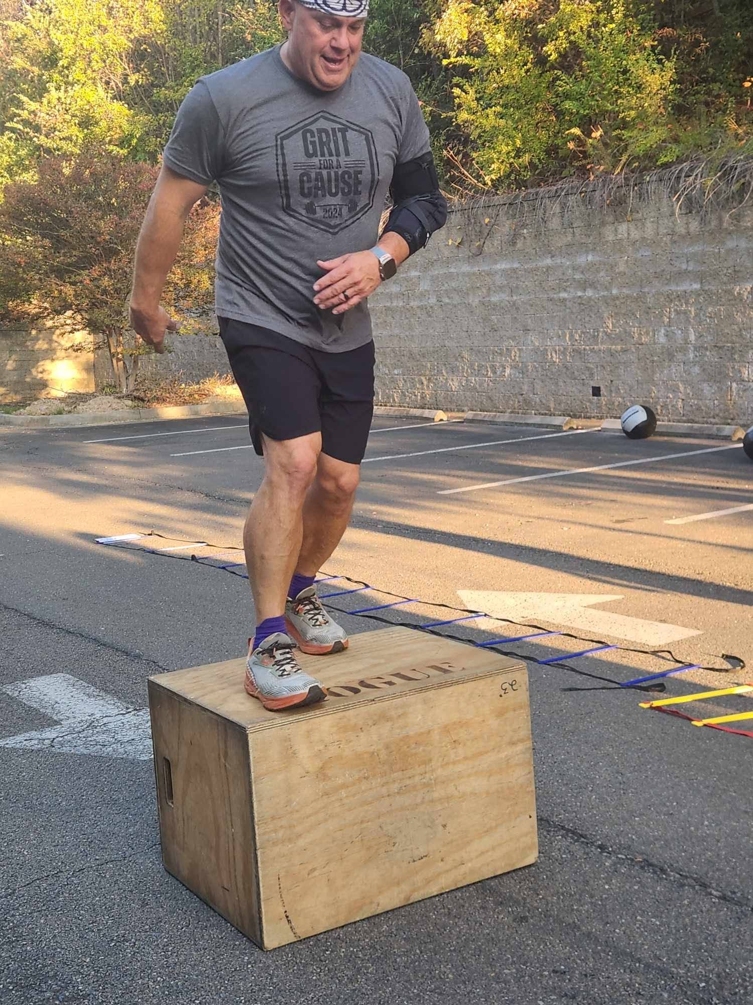 A participant stepping up onto a wooden plyo box during the challenge