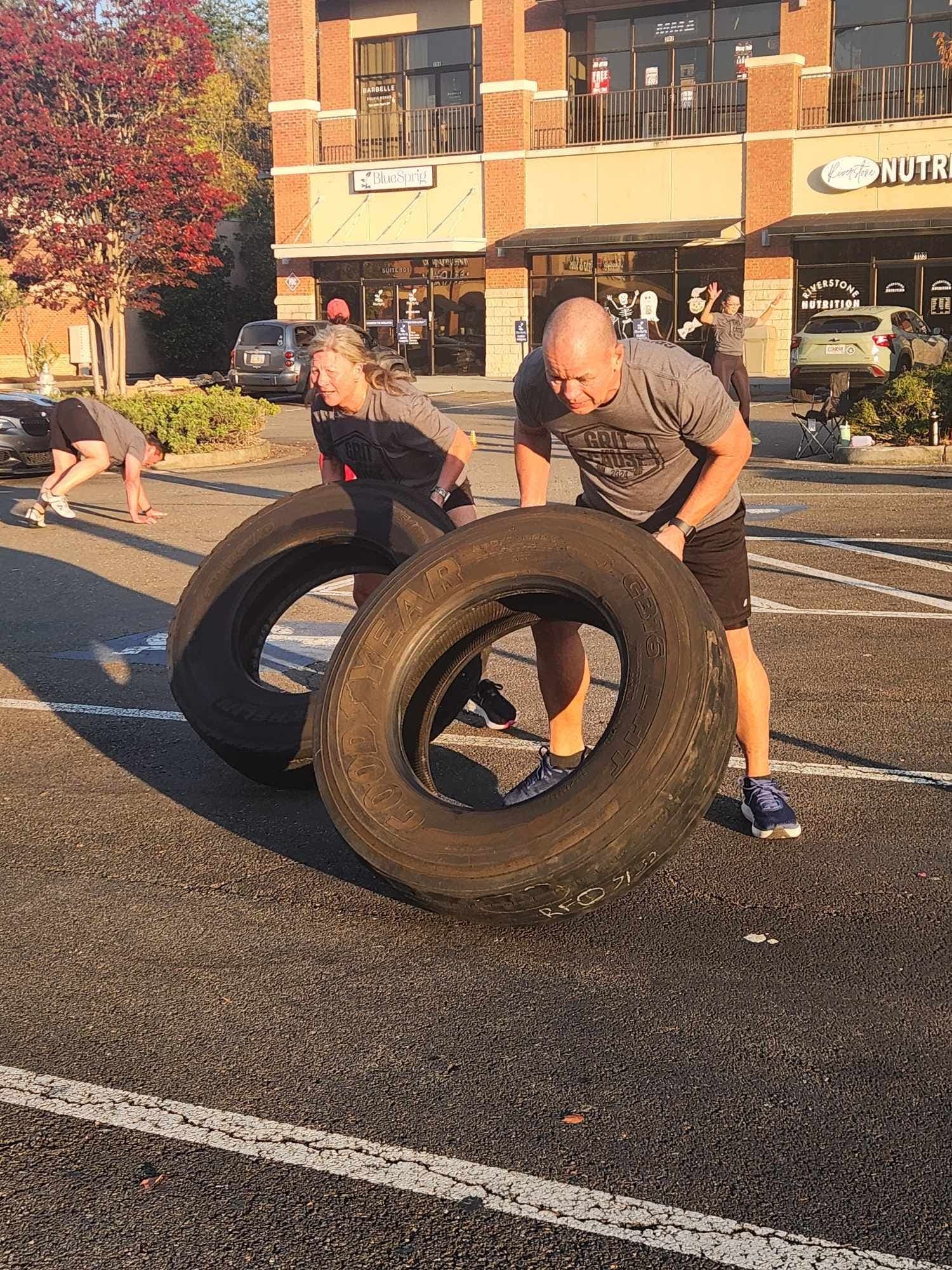 Two Grit for a Cause participants flipping heavy tires in the parking lot